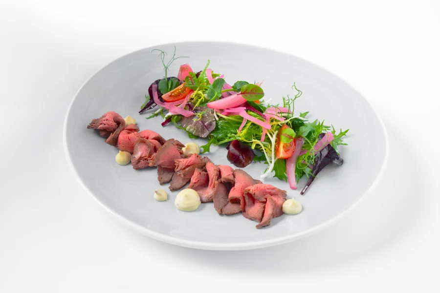 Green leaves salad with slices of beef tenderloin scented with truffles